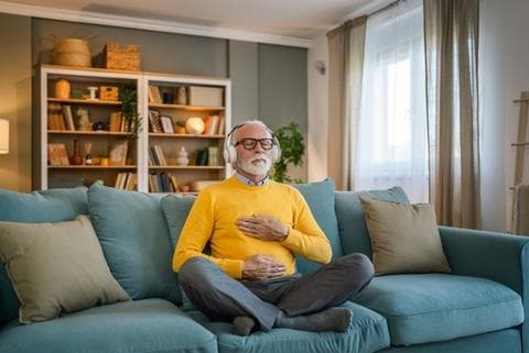 älterer-mann-meditiert-im-wohnzimmer
